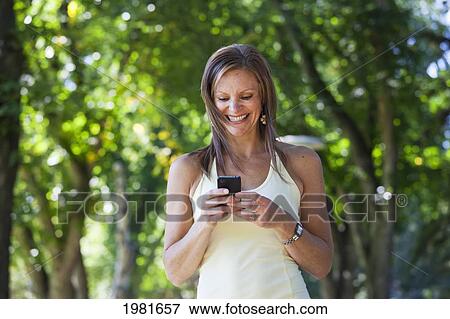 Stock Photo - woman walking and checking text messages; edmonton alberta canada. Fotosearch
