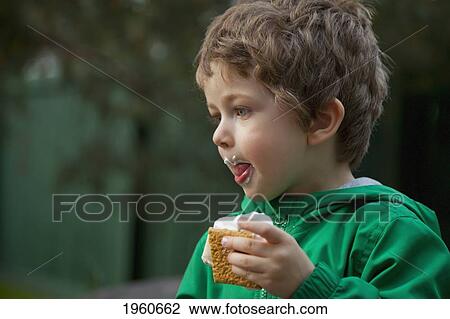 Stock Image - young boy eating a smore cookie; st. albert, alberta, canada. Fotosearch