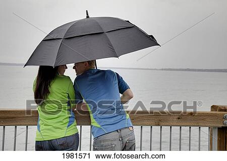 young couple on the water's edge under an umbrella; bellingham wasington united states of america View Large Photo Image Stock Image - young couple on the water's edge under an umbrella; bellingham wasington united states of america. Fotosearch