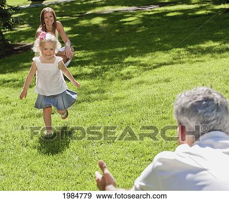 young girl running to her father in a park; edmonton alberta canada View Large Photo Image Stock Photo - young girl running to her father in a park; edmonton alberta canada. Fotosearch