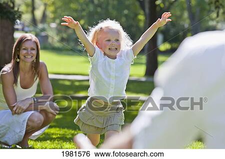 Stock Photograph - young girl running to her father in the park; edmonton alberta canada. Fotosearch