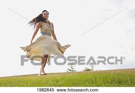 Stock Photography - young woman dancing in the park with a flowing dress; edmonton alberta canada. Fotosearch