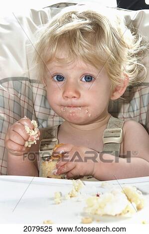Stock Photography - A baby girl celebrates her first birthday eating cake in her highchair; millet alberta canada. Fotosearch