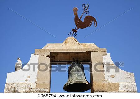 A Bird And Metal Rooster Sit Atop A Bell Tower; Faro Algarve Portugal View Large Photo Image Picture - A Bird And Metal Rooster Sit Atop A Bell Tower; Faro Algarve Portugal. Fotosearch