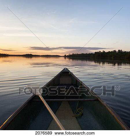 A boat and paddle on a tranquil lake at sunset; lake of the woods ontario canada View Large Photo Image Stock Photo - A boat and paddle on a tranquil lake at sunset; lake of the woods ontario canada. Fotosearch