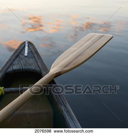 A boat and paddle sit on a tranquil lake with clouds reflected in the water; lake of the woods ontario canada View Large Photo Image Stock Photo - A boat and paddle sit on a tranquil lake with clouds reflected in the water; lake of the woods ontario canada. Fotosearch