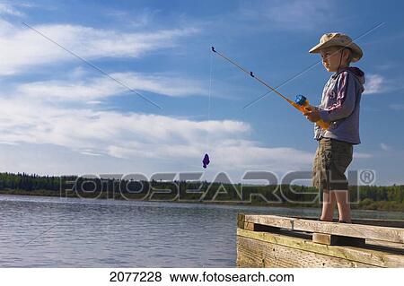 Stock Photo - A boy fishing off a dock; lake wabamun alberta canada. Fotosearch