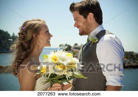 Stock Image - A bride and groom at the water's edge in whytecliff park; vancouver british columbia canada. Fotosearch