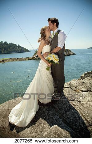 A bride and groom embrace at the water's edge in whytecliff park; vancouver british columbia canada View Large Photo Image Stock Photography - A bride and groom embrace at the water's edge in whytecliff park; vancouver british columbia canada. Fotosearch