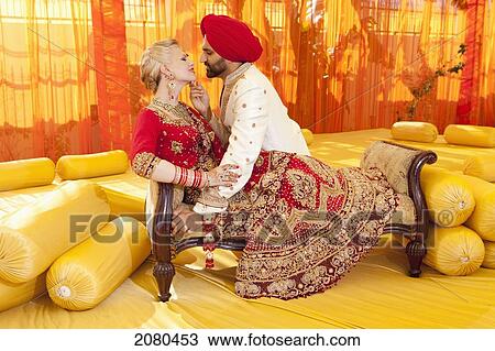 Stock Image - A bride and groom in traditional indian dress for their wedding ceremony; ludhiana punjab india. Fotosearch