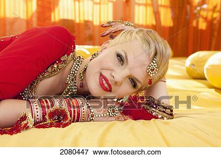 Stock Photo - A bride wearing an ornate gown and jewelry with her hands covered in mehndi; ludhiana punjab india. Fotosearch