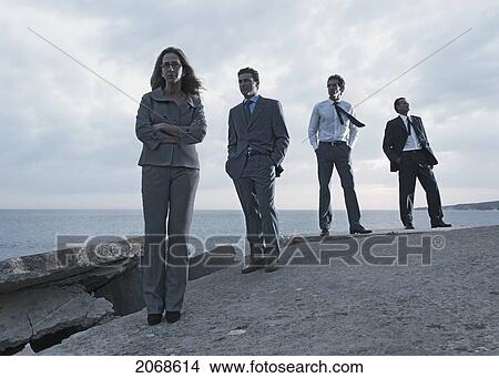 A Businesswoman And Three Businessmen Lined Up Along The Water's Edge; Tarifa Cadiz Andalusia Spain View Large Photo Image Picture - A Businesswoman And Three Businessmen Lined Up Along The Water's Edge; Tarifa Cadiz Andalusia Spain. Fotosearch