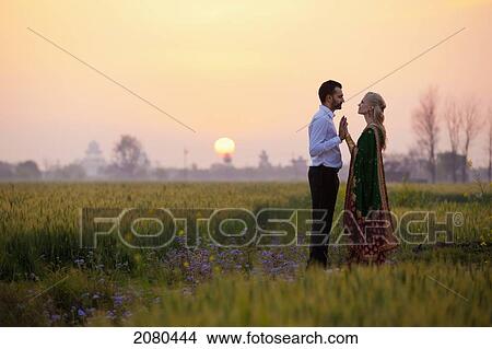 Picture - A couple standing face to face in a field at sunset; ludhiana punjab india. Fotosearch