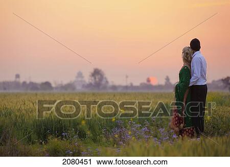 A couple standing together in a field at sunset; ludhiana punjab india View Large Photo Image Stock Image - A couple standing together in a field at sunset; ludhiana punjab india. Fotosearch