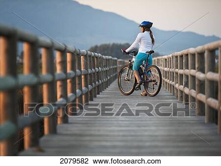 Stock Image - A cyclist on a wooden boardwalk; tarifa cadiz andalusia spain. Fotosearch