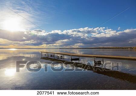 Stock Image - A dock leading out into the lake at sunrise; pigeon lake alberta canada. Fotosearch