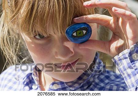 A girl holding a painted eye up to her eye; lake of the woods ontario canada View Large Photo Image Stock Photography - A girl holding a painted eye up to her eye; lake of the woods ontario canada. Fotosearch
