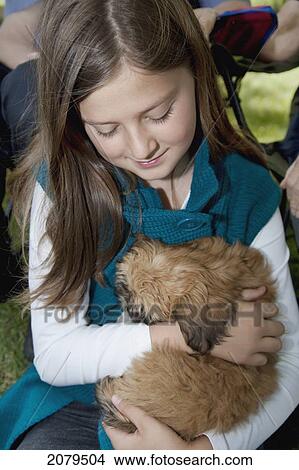 Picture - A girl holds a puppy in her lap; edmonton alberta canada. Fotosearch