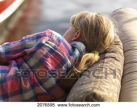 A girl rests on a cushioned couch outdoors beside the water; lake of the woods ontario canada View Large Photo Image Stock Photography - A girl rests on a cushioned couch outdoors beside the water; lake of the woods ontario canada. Fotosearch