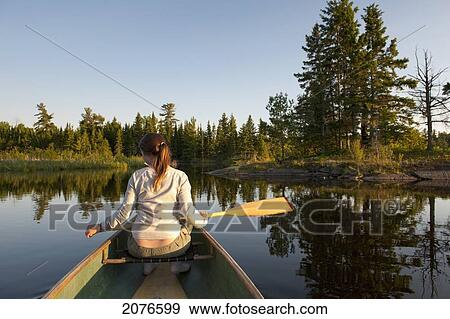 A girl sits in a boat with a paddle on a tranquil lake; lake of the woods ontario canada View Large Photo Image Stock Photo - A girl sits in a boat with a paddle on a tranquil lake; lake of the woods ontario canada. Fotosearch