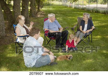 Stock Photo - A group of people sit on the lawn visiting; edmonton alberta canada. Fotosearch