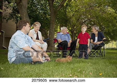 Stock Photography - A group of people sit on the lawn visiting; edmonton alberta canada. Fotosearch