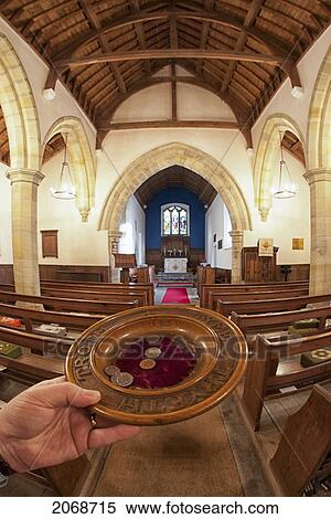 Stock Photography - A Hand Holds An Offering Plate At The Back Of A Church; Northumberland England. Fotosearch