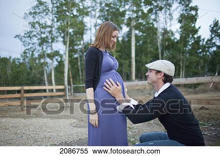 Stock Photography - A husband putting his hands on his wife's pregnant belly; sherwood park alberta canada. Fotosearch