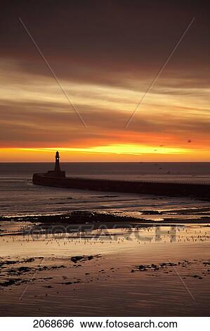 Stock Photograph - A Lighthouse At Water's Edge At Sunset; Roker Sunderland Tyne And Wear England. Fotosearch