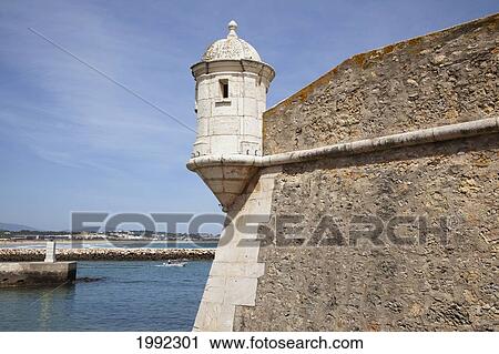 Stock Image - A Lookout Posted In The Corner Of A Stone Wall On The Water's Edge; Lago Algarve Portugal. Fotosearch