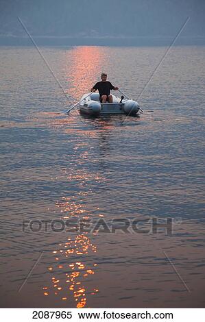 A man rows his dinghy in pendrell sound as the sun sets; british columbia canada View Large Photo Image Stock Photography - A man rows his dinghy in pendrell sound as the sun sets; british columbia canada. Fotosearch