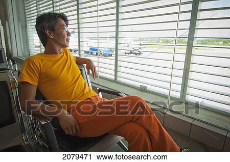 A man sits in a chair in an airport looking out the window; puerto rico View Large Photo Image Stock Image - A man sits in a chair in an airport looking out the window; puerto rico. Fotosearch