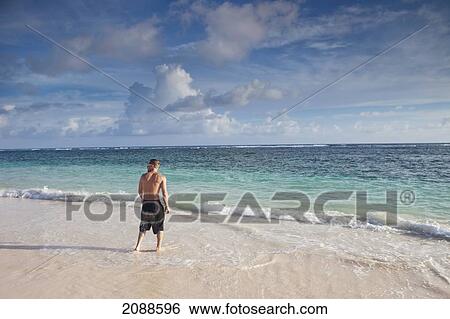 A man stands on a beach with the water washing up on his feet; punta cana la altagracia dominican republic View Large Photo Image Stock Photograph - A man stands on a beach with the water washing up on his feet; punta cana la altagracia dominican republic. Fotosearch