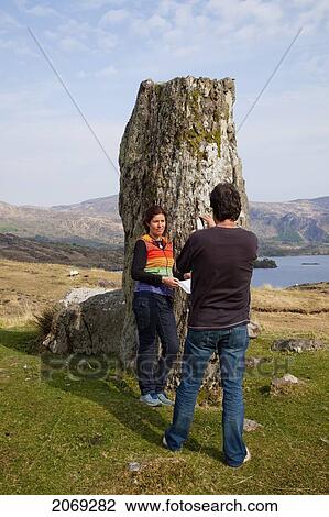 A Man Taking A Picture Of A Woman Beside A Rock Formation On The Coast Near Kenmare; County Kerry Ireland View Large Photo Image Stock Image - A Man Taking A Picture Of A Woman Beside A Rock Formation On The Coast Near Kenmare; County Kerry Ireland. Fotosearch