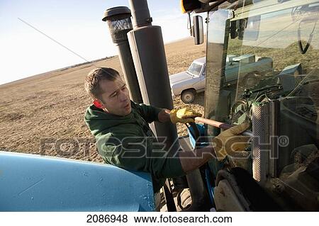 A man washing the window on farm equipment; three hills alberta canada View Large Photo Image Stock Photo - A man washing the window on farm equipment; three hills alberta canada. Fotosearch