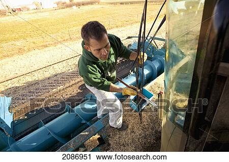 Stock Image - A man washing the windows on farm equipment; three hills alberta canada. Fotosearch