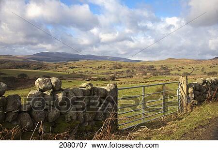 A metal gate in a stone wall with a landscape of rolling hills; dumfries scotland View Large Photo Image Stock Photo - A metal gate in a stone wall with a landscape of rolling hills; dumfries scotland. Fotosearch