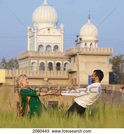 A mixed race couple holding hands in a field with a temple in the background; ludhiana punjab india View Large Photo Image Stock Image - A mixed race couple holding hands in a field with a temple in the background; ludhiana punjab india. Fotosearch