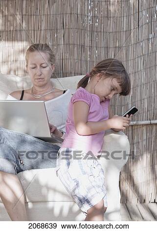 A Mother And Daughter Focused On Separate Things; Tarifa Cadiz Andalusia Spain View Large Photo Image Stock Photo - A Mother And Daughter Focused On Separate Things; Tarifa Cadiz Andalusia Spain. Fotosearch