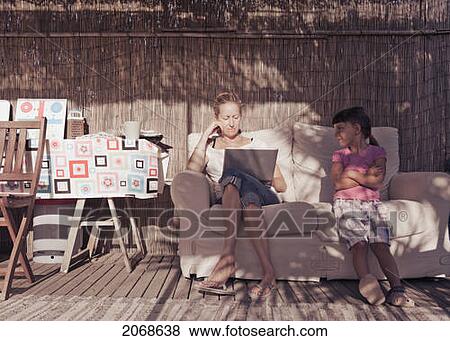 A Mother And Daughter Sit Together On A Couch While The Mother Works On A Laptop Computer; Tarifa Cadiz Andalusia Spain View Large Photo Image Stock Photo - A Mother And Daughter Sit Together On A Couch While The Mother Works On A Laptop Computer; Tarifa Cadiz Andalusia Spain. Fotosearch