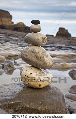 Stock Image - A pile of rocks balancing from largest to smallest on a boulder at the water's edge; south shields tyne and wear england. Fotosearch