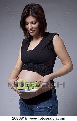 A pregnant woman holds us a pregnancy test and a sign saying 'live' beside her bare pregnant belly; edmonton alberta canada View Large Photo Image Stock Photo - A pregnant woman holds us a pregnancy test and a sign saying 'live' beside her bare pregnant belly; edmonton alberta canada. Fotosearch