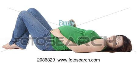 Stock Photo - A pregnant woman lays on her back with a sign saying 'family' on her belly; edmonton alberta canada. Fotosearch