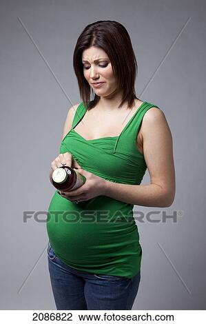 A pregnant woman reading the label on a bottle; edmonton alberta canada View Large Photo Image Stock Image - A pregnant woman reading the label on a bottle; edmonton alberta canada. Fotosearch