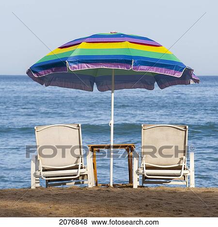 A Rainbow Beach Umbrella Over Two Lounge Chairs On The At Beach Umbrella Over Two Lounge Chairs