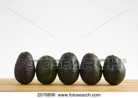 A row of avocados standing upright on a wooden board; calgary alberta canada View Large Photo Image Stock Photograph - A row of avocados standing upright on a wooden board; calgary alberta canada. Fotosearch