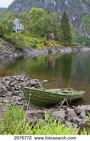 A rowboat sits on the shore of a tranquil lake; norway View Large Photo Image Stock Image - A rowboat sits on the shore of a tranquil lake; norway. Fotosearch