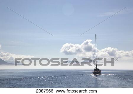 Stock Photograph - A sailboat cruises on a sunny day in the gulf islands; british columbia canada. Fotosearch