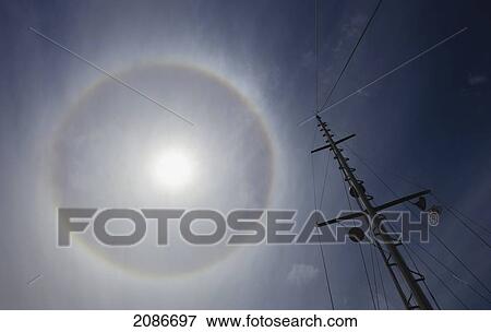 Stock Photo - A sailboat mast is in the foreground of a sun dog; vancouver island british columbia canada. Fotosearch
