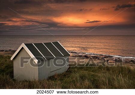 Stock Photo - A Small Building On The Water's Edge At Sunset; Bamburgh Northumberland England. Fotosearch